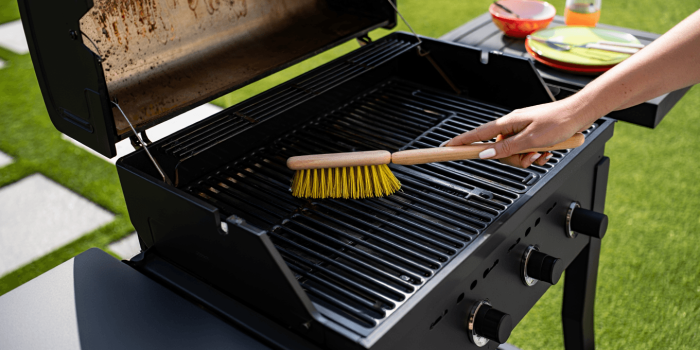 Un homme qui nettoie une grille de barbecue avec une brosse