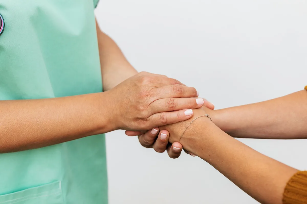 Deux personnes se tenant les mains en signe de soutien et de compassion
