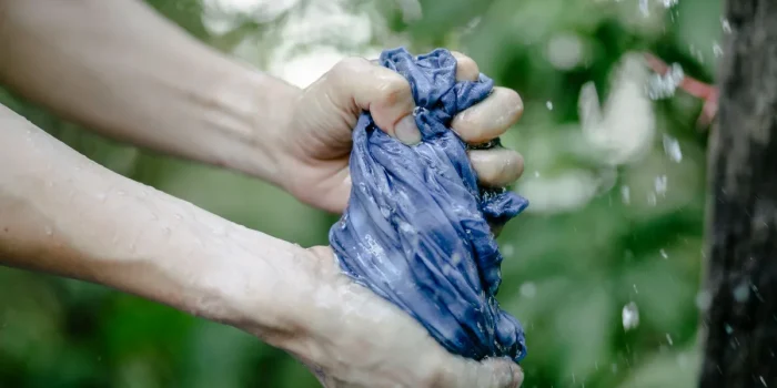 Mains appliquant une poudre blanche sur une tache de transpiration sur un vêtement