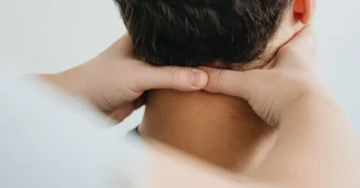Mains d'un praticien effectuant une manipulation douce sur le dos d'une personne âgée en cabinet