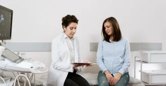 Femme en consultation médicale, documents médicaux sur le bureau, expression préoccupée