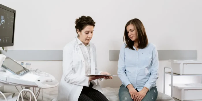 Femme en consultation médicale, documents médicaux sur le bureau, expression préoccupée