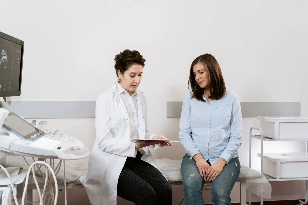 Femme en consultation médicale, documents médicaux sur le bureau, expression préoccupée