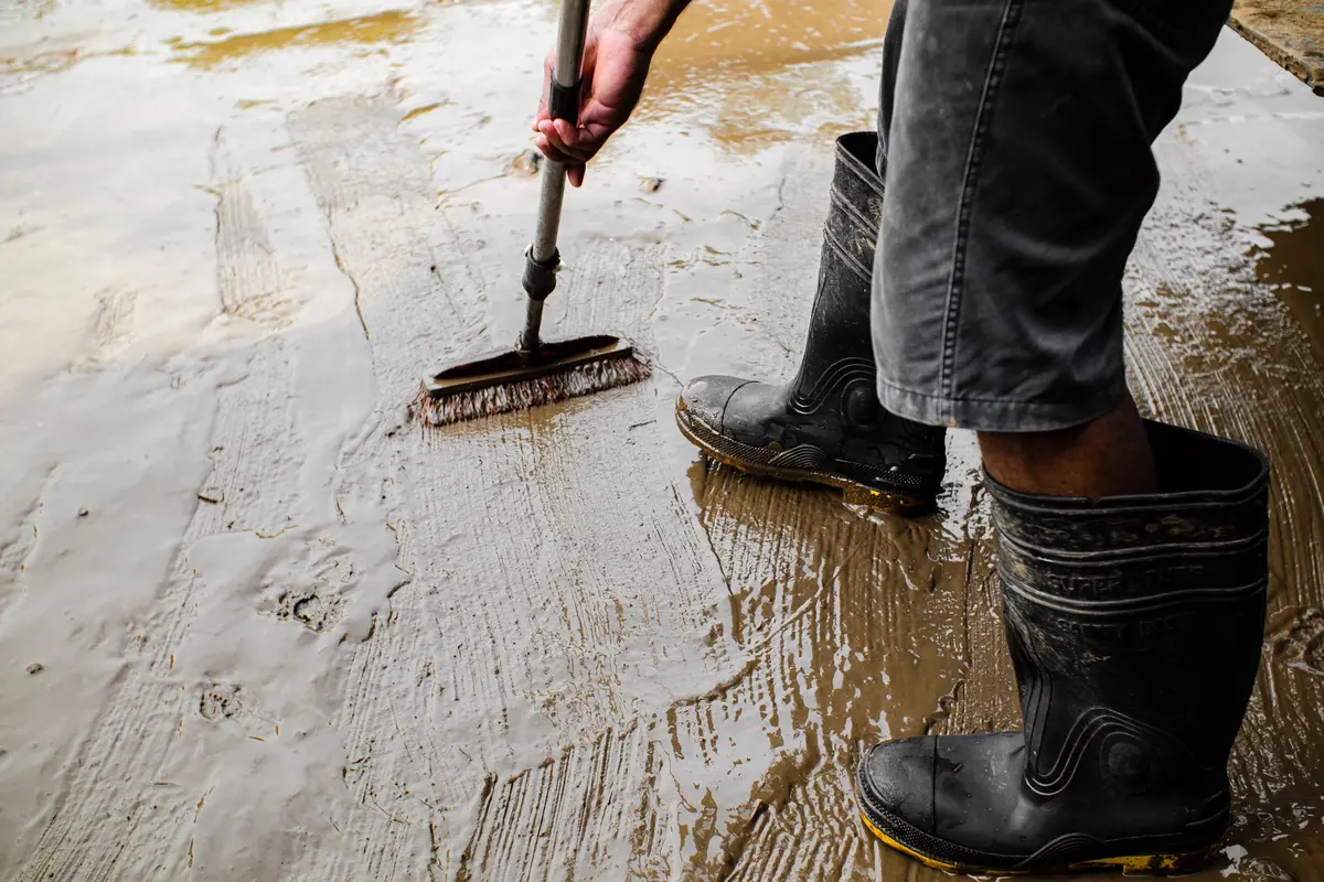 Brosse à poils durs frottant une tache d'huile sur béton