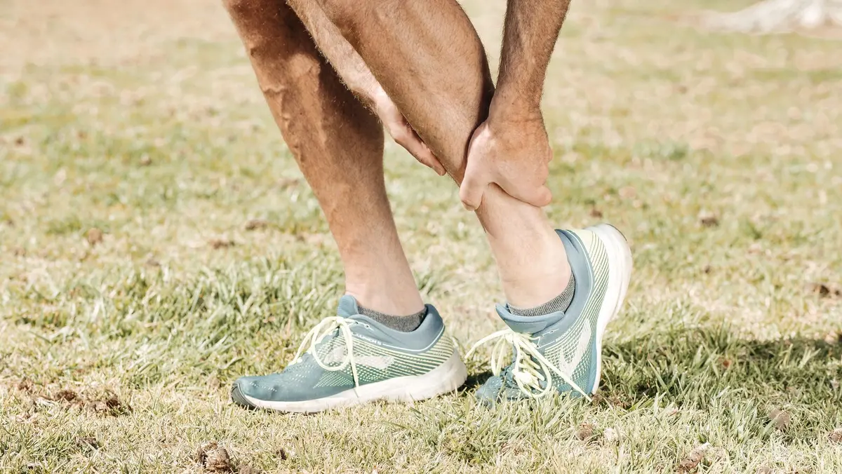 Coureur en entraînement intensif ressentant une fatigue musculaire aux jambes