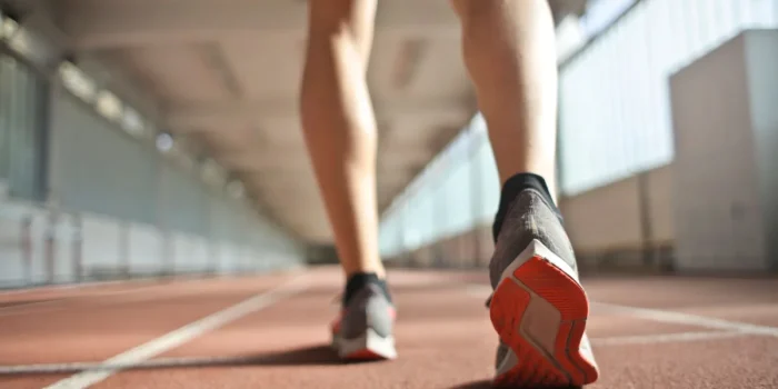 Coureur en chaussure de sport sur piste d'entraînement, montrant l'effort et la charge répétée