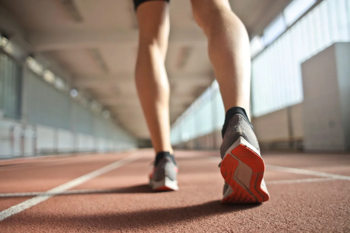 Coureur en chaussure de sport sur piste d'entraînement, montrant l'effort et la charge répétée