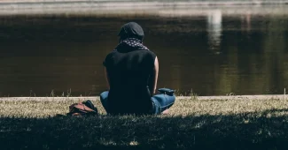 Personne assise seule dans une pièce calme, le visage entre les mains, exprimant la réflexion et le poids émotionnel.