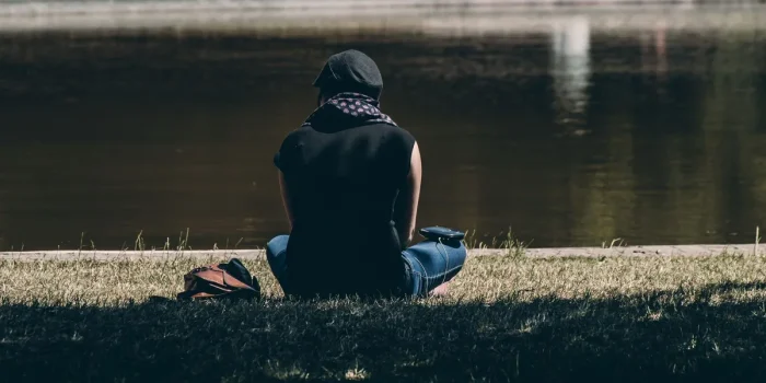 Personne assise seule dans une pièce calme, le visage entre les mains, exprimant la réflexion et le poids émotionnel.