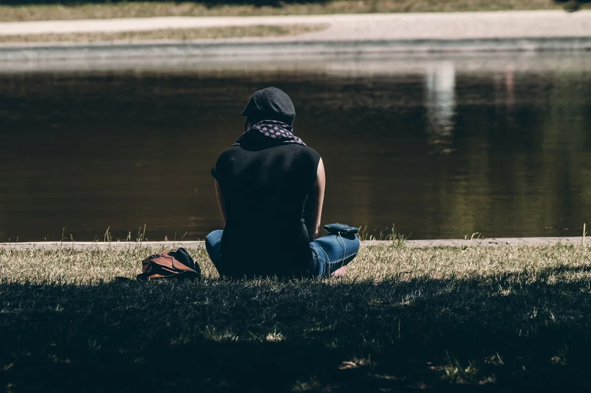 Personne assise seule dans une pièce calme, le visage entre les mains, exprimant la réflexion et le poids émotionnel.