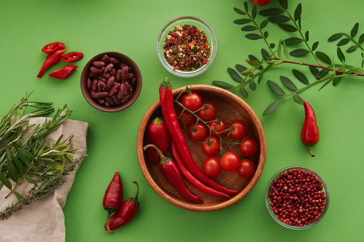 Mains préparant des légumes colorés et des herbes aromatiques sur un plan de travail en bois