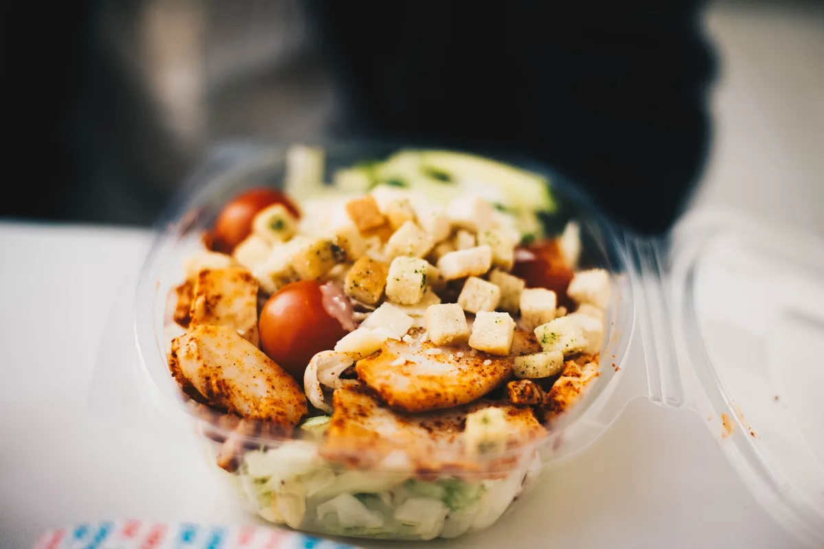 Verre contenant un shake protéiné à côté d'une assiette de repas équilibré