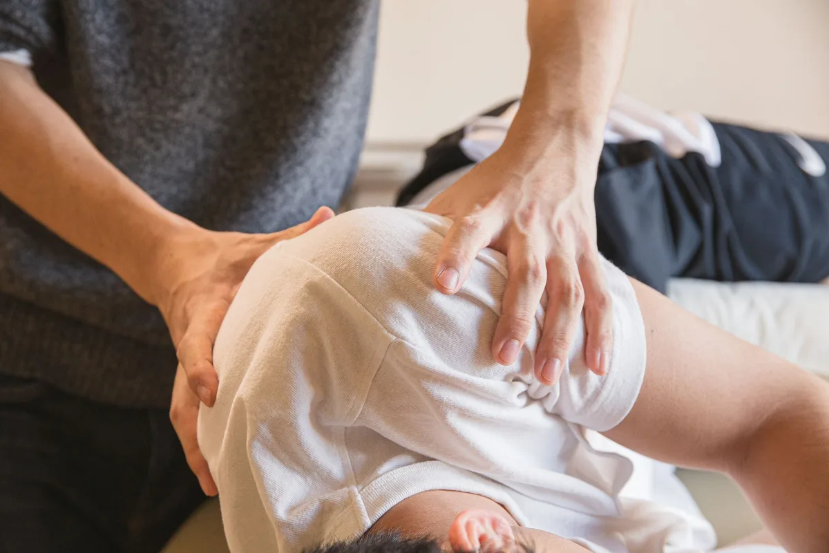 Mains d'un ostéopathe pratiquant une technique crânienne légère sur la tête d'un patient