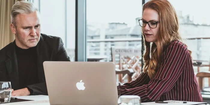 Deux professionnels en discussion réfléchie dans un cadre de bureau neutre