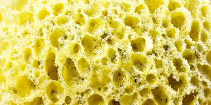 Personne nettoyant le filtre d'une machine à laver avec une brosse, eau résiduelle visible