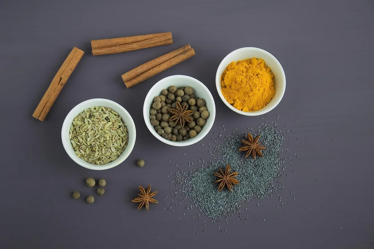 Racines de curcuma et poudre sur un plateau, évoquant l'origine et la transformation