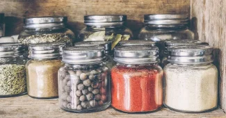 Bocaux anonymes d'ingrédients naturels et chiffon sur planche de cuisine