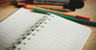 Mains anonymes tenant des notes de cas clinique sur un bureau de thérapeute avec cahier ouvert