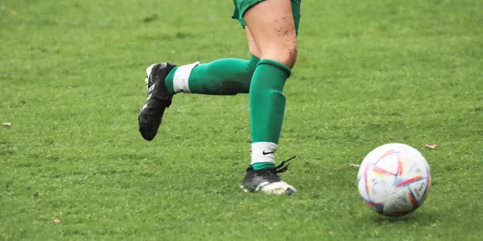 Joueur de football en action lors d'un match intense, jambes en mouvement dynamique.